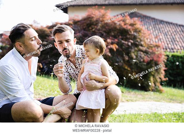 Gay couple playing with their child in the garden
