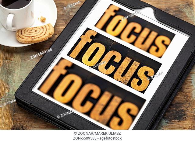 focus word in and out of focus - text in vintage letterpress wood type on a digital tablet with a cup of coffee
