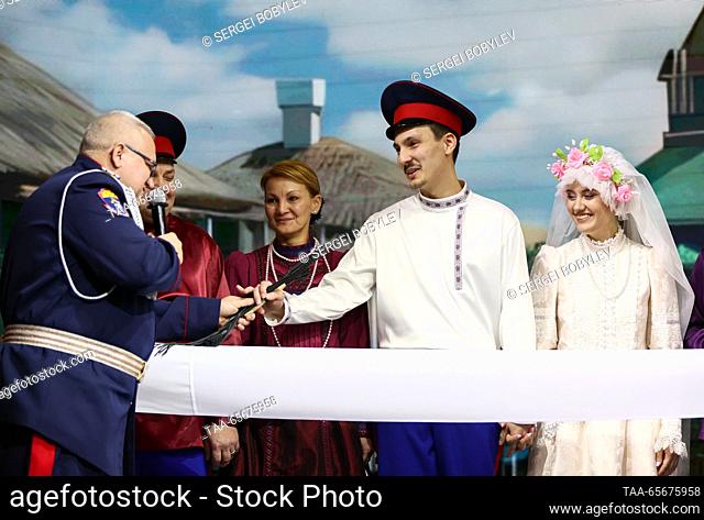 RUSSIA, MOSCOW - DECEMBER 12, 2023: Newlyweds Vladislav Kapustinsky (C) and Alexandra Semenenko (R) are seen at a Don Cossack wedding during the Russia Expo...