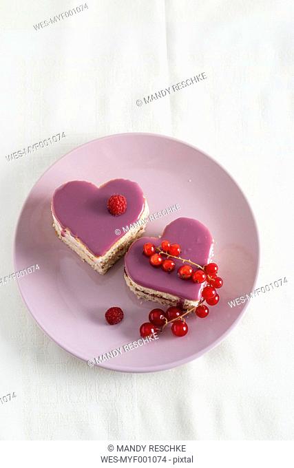 Small biscuit cakes in heart shape with raspberry cream and currant jelly