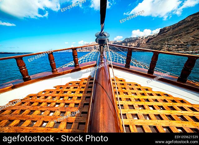 On board view from a traditional ship cruising on Aegean sea next to Santorini island. Wooden deck, sunny summer day