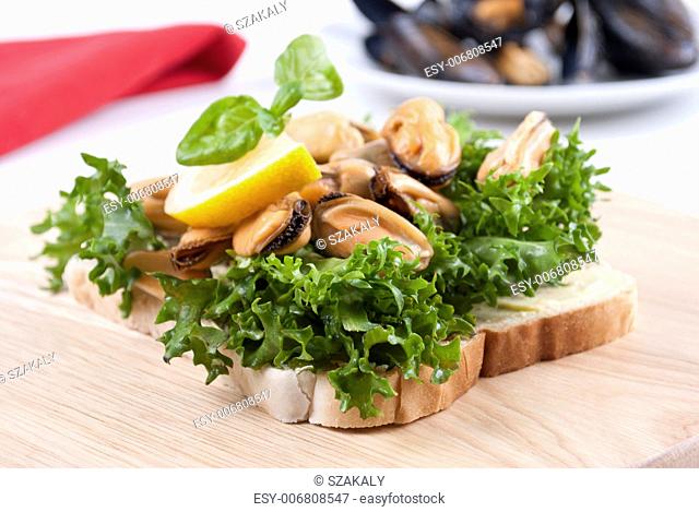 Cooked mussels with lemon, fresh salad on toast