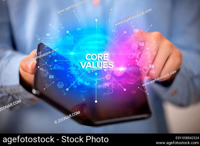 Businessman holding a foldable smartphone with CORE VALUES inscription, new business concept