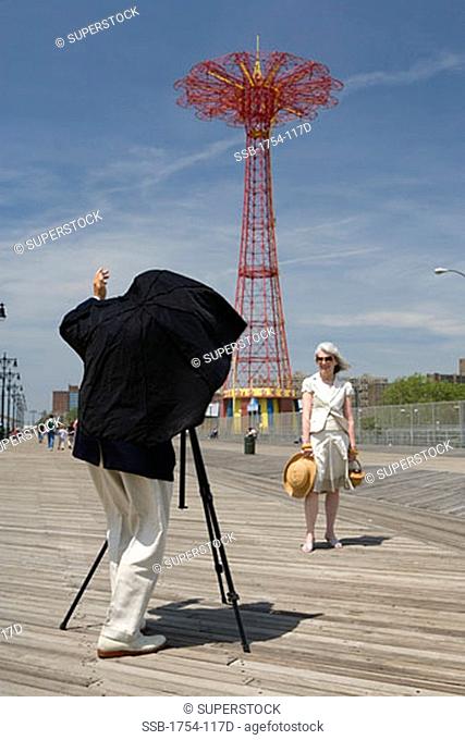 Senior man photographing a senior woman, Parachute Drop, Coney Island, New York City, New York, USA
