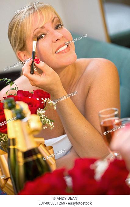 Blonde Woman Applies Makeup at Mirror Near Champagne and Roses