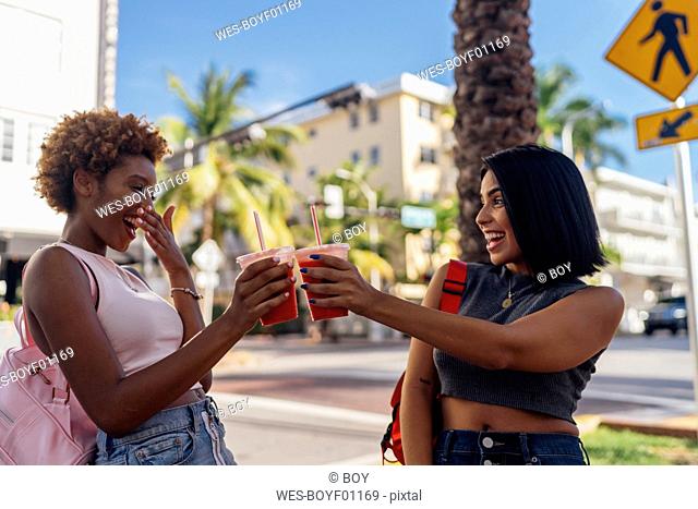USA, Florida, Miami Beach, two happy female friends having a soft drink in the city