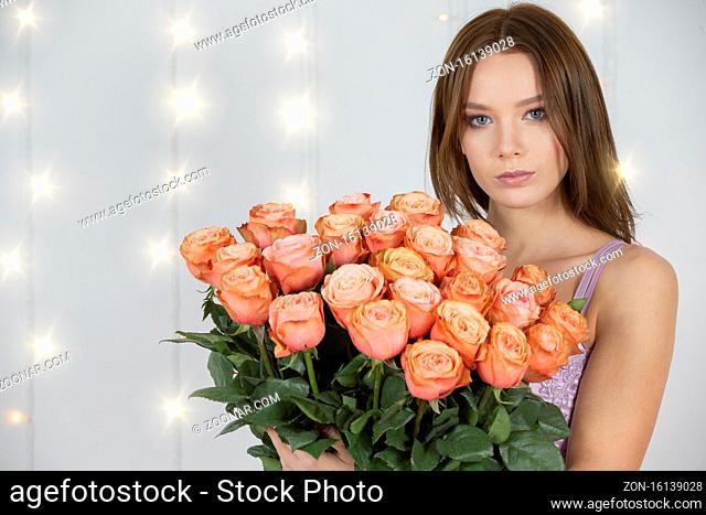 Portrait of a young beautiful girl with a bouquet of roses