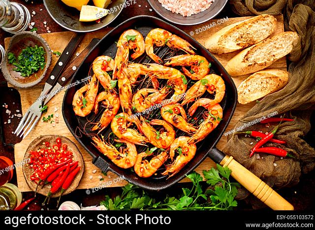 Tasty appetizing roasted shrimps prawns with spices on pan with ingredients on rusty background. Top View, flat lay. Background Seafood Kitchen Concept