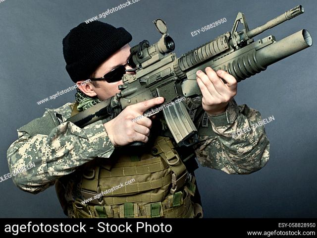 US soldier in black goggles aiming with his rifle