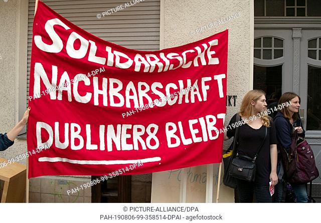 06 August 2019, Berlin: Participants in a protest against the eviction of an apartment on Dubliner Straße 8 in Wedding are standing with a banner in front of...