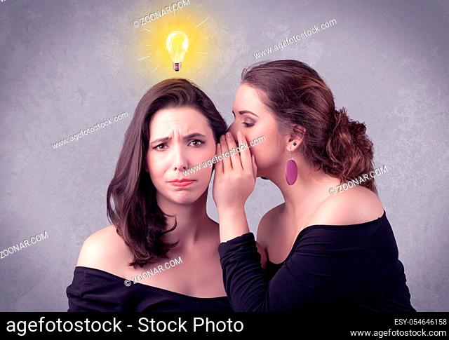 A young girl has an idea illustrated with a drawn glowing light bulb above the head, while a friend whispers a secret in her ear concept