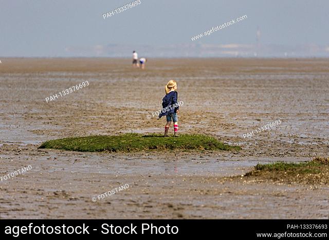 Harlesiel / Carolinensiel, Germany June 2020: Symbolic images - 2020 A little girl stands at low tide on an elevation overgrown with algae in the Wadden Sea in...