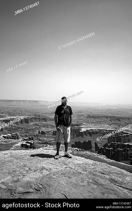Man standing at Grand View Point. Scenic pullout & easy 2-mi. hike along the mesa rim with sweeping vistas of dramatic canyon terrain in Canyonlands National...