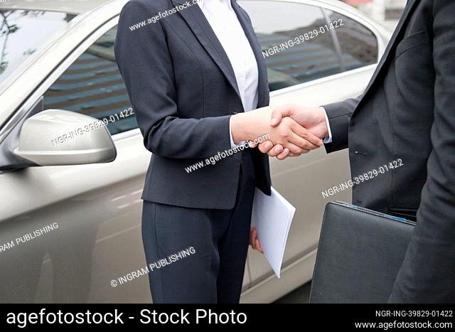 Business People Shaking Hands By Car