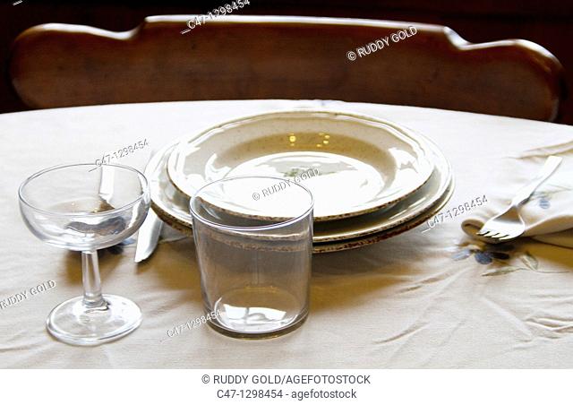 Table set with plates, cups, glasses, cover, tablecloth, spoons, forks and knives