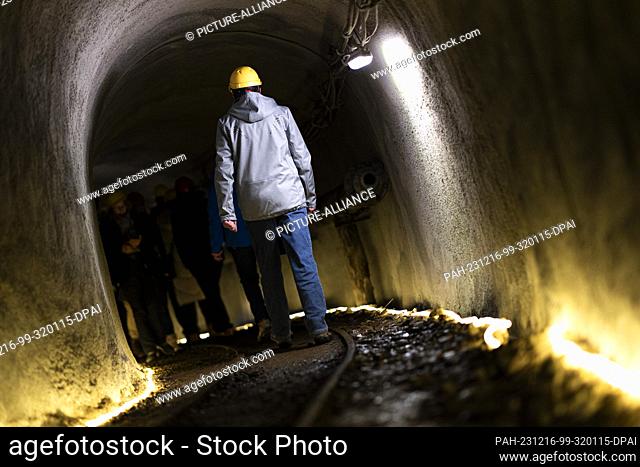 16 December 2023, Lower Saxony, Goslar: Visitors wearing hard hats walk through a tunnel from the Rammelsberg Mining Museum to get to the Christmas market