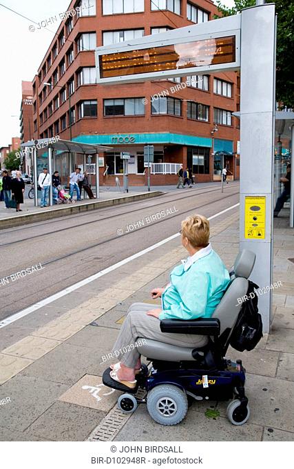 Woman wheelchair user waiting at a tram stop