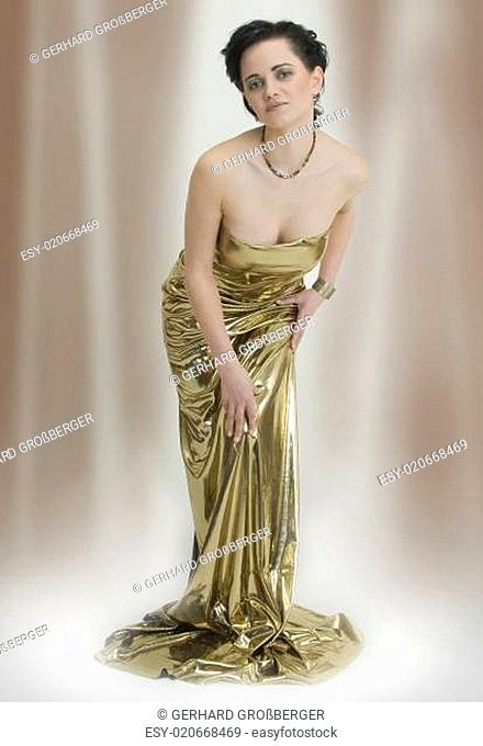 Junge elegante schlanke Frau in Kleid aus Gold