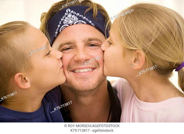 children kissing dad on cheeks