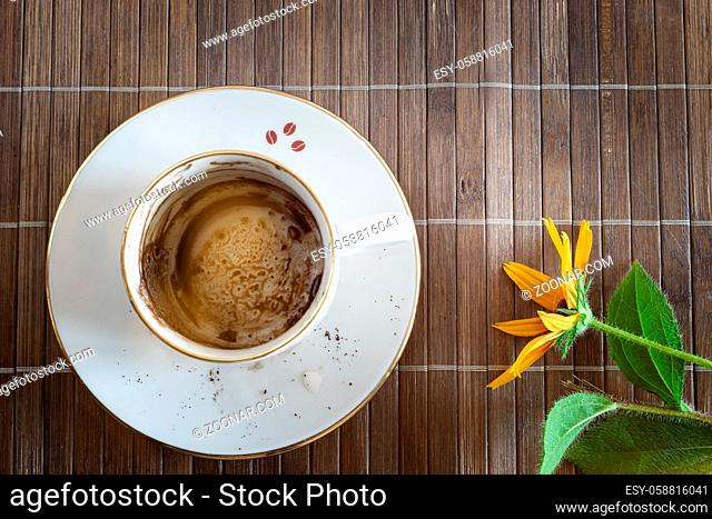 There is a dirty Cup and saucer on a bamboo stand after drinking coffee. Top view, copy space