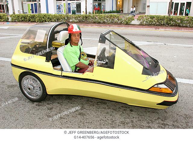 Hispanic male driver, three wheel car. South Beach, Miami Beach, Florida. USA