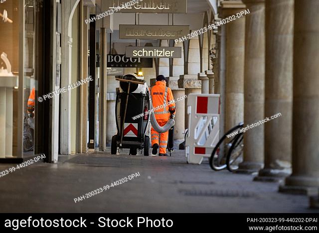 23 March 2020, North Rhine-Westphalia, Münster: An employee of the street cleaning service goes through the Prinzipalmarkt