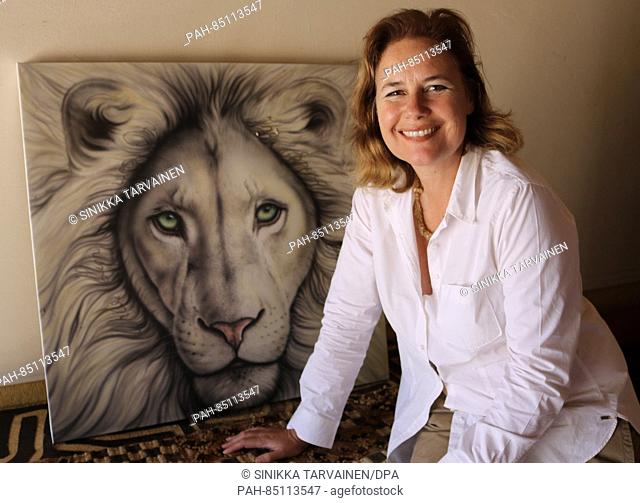 CEO of the Global White Lion Trust, Linda Tucker, who operates a conservancy for while lions in South Africa, sits in front of a painting of a white lion in...