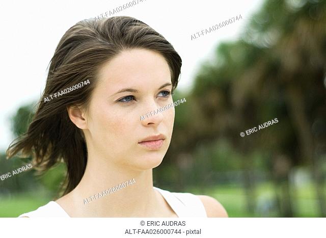 Teen girl looking away, hair blowing in wind, head and shoulders