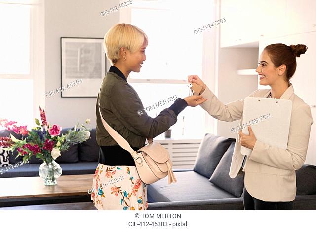 Real estate agent giving apartment keys to young woman