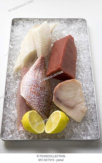 Assorted fish fillets with lemon on ice