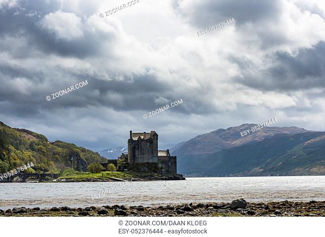 castle Eilean Donan in the Scottish Higlands with dark clouds, sunlight and ocean