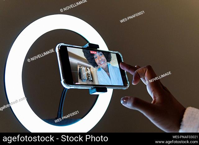 Smiling woman vlogging on smart phone in illuminated ring light