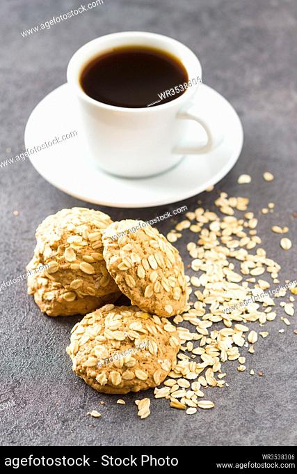 Healthy oatmeal cookies and cup of coffee obn black table