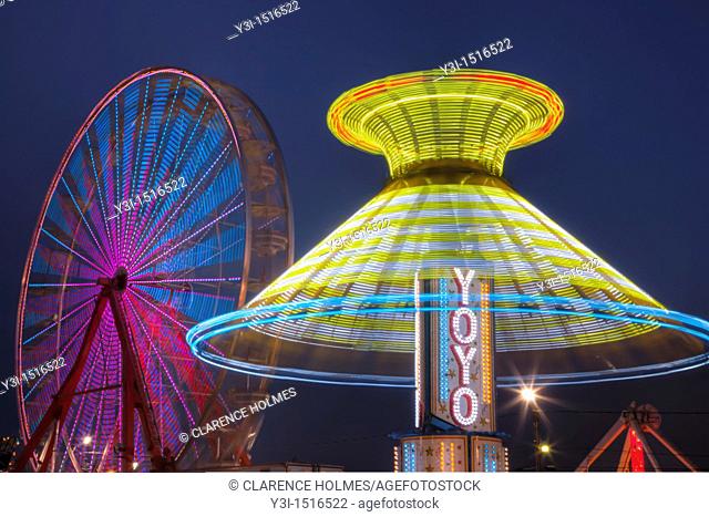 AUGUSTA, NJ - AUGUST 13: The colorfully illuminated Yo Yo spins in front of the Gentle Giant Ferris Wheel against the night sky during the New Jersey State Fair...