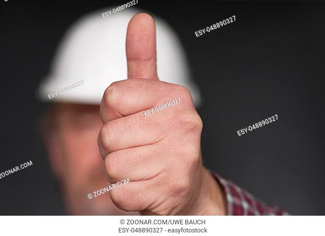 Positive Emotion, Bauarbeiter zeigt Hand mit Daumen hoch, geringe Tiefenschaerfe