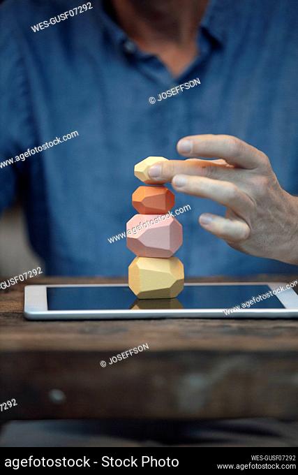 Businessman balancing stack of stones on tablet PC