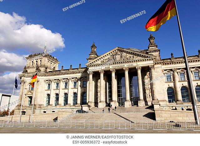 The Reichstag German Parlament building with German and EU flags streaming in the wind outside in Berlin, Germany