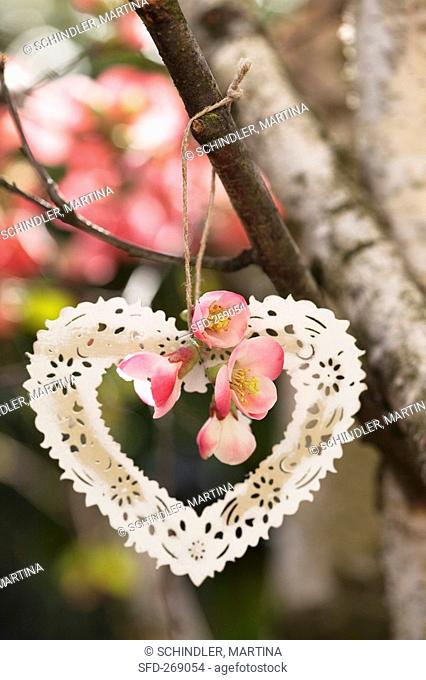 A metal heart and japonica hanging on a tree