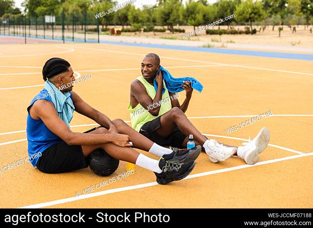 Father and son taking break sitting at basketball court