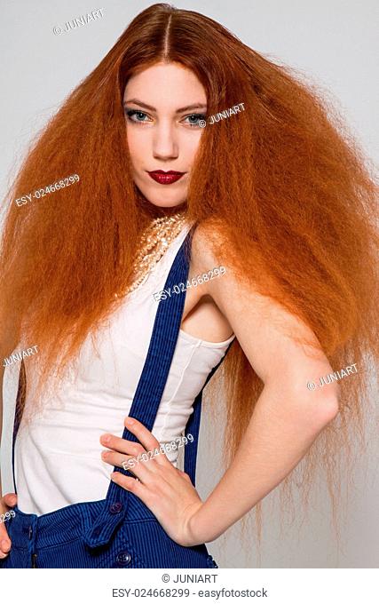 Female model with red lipstick playing with frizzy hair on white background