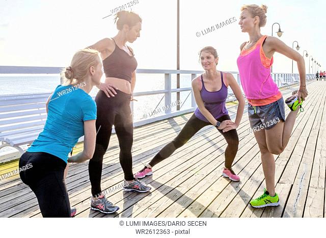 Group of women stretching legs on jetty