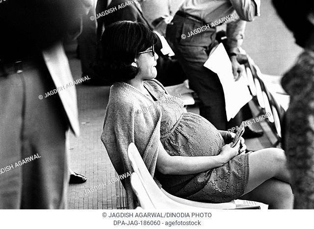 Anxious sitting pregnant woman at race course Hong Kong 1971