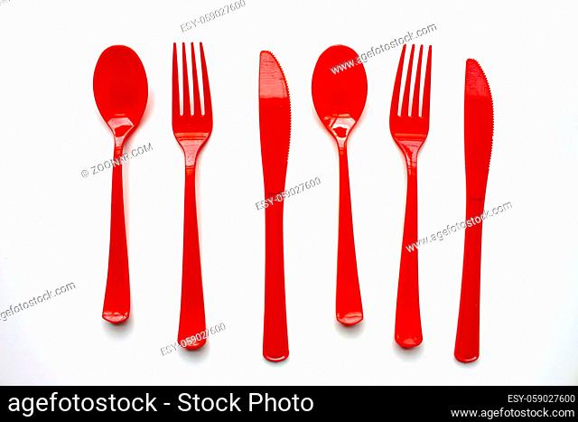 Single use red plastic cutlery on a white background. Concept: Ban single use plastic