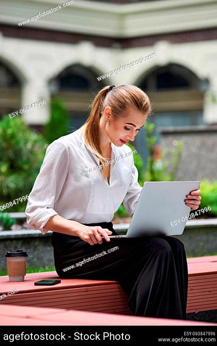 beautiful business woman working at the computer outdoors in sunny day