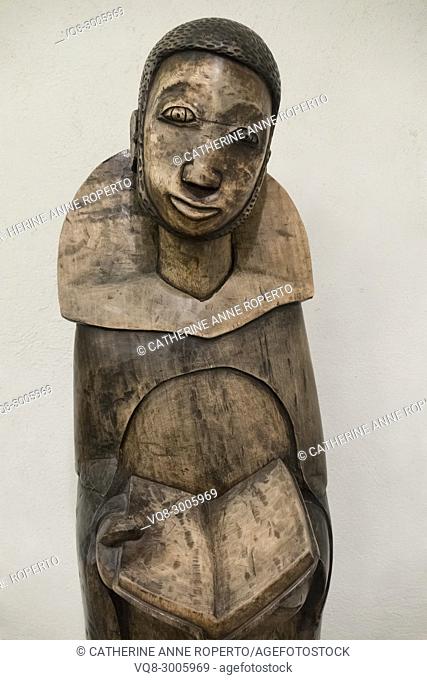 Polished wooden carving of African saint holding an open Bible in the crypt chapel of St Martin-in-the-Fields, Trafalgar Square, London, England