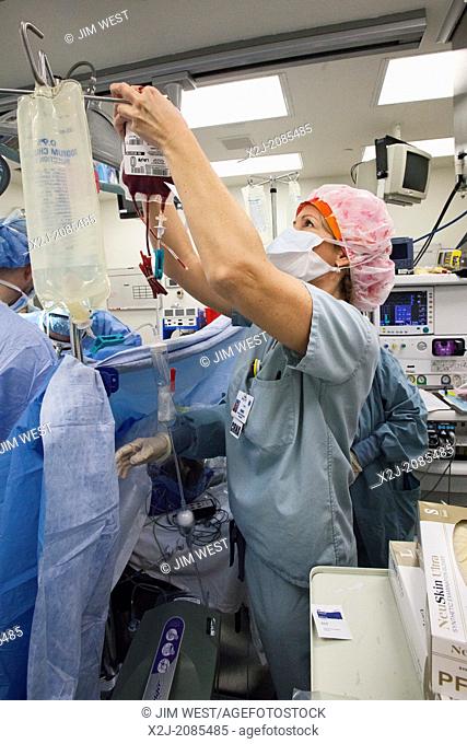 Detroit, Michigan - Certified Registered Nurse Anesthetist Amy Kiser hangs blood for a patient as surgeons perform a hysterectomy on a woman with endometrial...