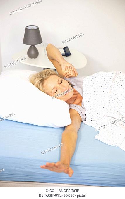 Woman waking up in her bed and stretching