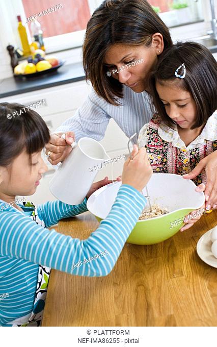 Mother baking with girls in kitchen