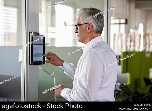 Businessman using device while standing by office door