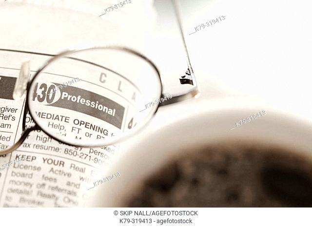 Glasses laying on classified ads with coffee